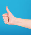 Right hand showing thumb up on blue background