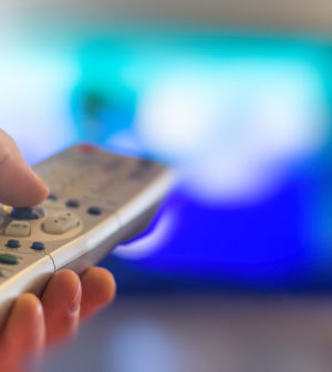 Close up of remote in hand with shallow depth of field during television watching